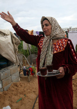 فلسطينية تحمل الشاي لعائلتها في الخيمة الثلاثاء الماضي (عادل حنا - أ ب)