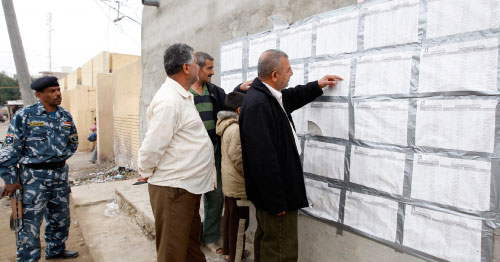 مواطنون يطلعون على لوائح المرشحين أمام مركز اقتراع في بغداد (ثائر السوداني ـ رويترز)
