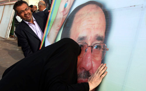 عراقية تقبل صورة المالكي الذي يترأس «ائتلاف دولة القانون» (كريم كاظم - أ ب)