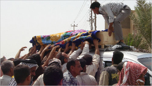 عراقيون ينقلون جثة أحد ضحايا تفجيرات يوم أمس (رويترز)