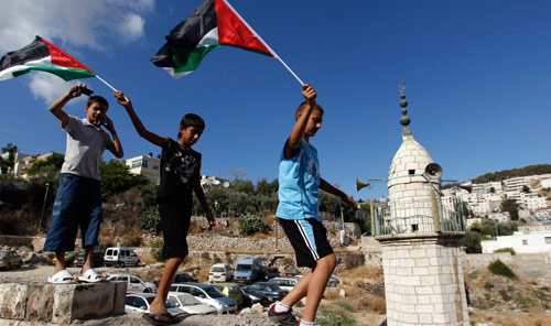 فتية يرفعون العلم الفلسطيني خلال مشاركتهم في تظاهرة ضد الإستيطان في حي سلوان الأسبوع الماضي (باز راتنر - رويترز) 