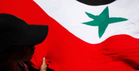 العلم السوري مرفوعاً خلال تظاهرة ضد النظام في مدريد (سوزانا فارا - رويترز)  