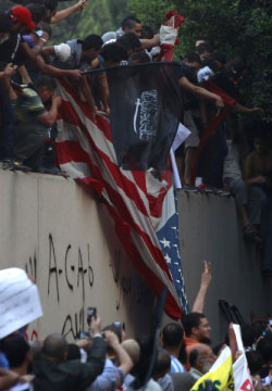 المتظاهرون خلال انزال العلم الأميركي أمس (عمر عبد الله دلش ـ رويترز)  
