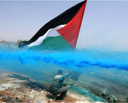 فلسطيني يصارع مياها ملونة  خلال تظاهرة ضد جدار الفصل في قرية بلعين أمس