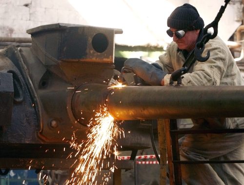عامل جورجي يقطّع مدفع دبّابة «تي - 55» سوفياتيّة الصنع في تبيليسي (أرشيف - رويترز)