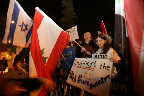 ناشط من اليسار الإسرائيلي يحمل علماً لبنانياً خلال التظاهرة أمام مكتب أولمرت في القدس أمس (أ ف ب)
