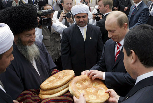 بوتين والرئيس التركماني يقطعان الخبز التركماني التراثي في عشق أباد أمس (ميخائيل كليمنتييف - إي بي إي)