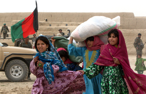 أفغانيات يحملن مساعدات إنسانية يوزّعها الجيش الأفغاني غرب كابول أمس (مصادق صادق - أ ب)