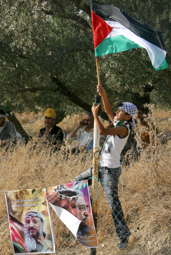طفل يرفع علماً فلسطينياً خلال مهرجان لـ «فتح» قرب نابلس أمس (جعفر اشتيه - أ ف ب)