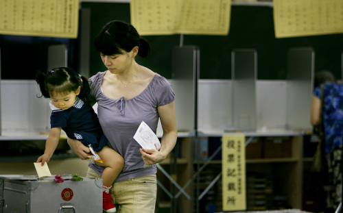 يابانيّة تدلي بصوتها مع ابنتها في مركز اقتراع في طوكيو أمس (جونجي كوروكوا - أ ب)