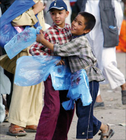 طفلان أفغانيان يلهوان أثناء بيع أكياس في أحد أسواق كابول أمس (ساراباه داي - أ ب)