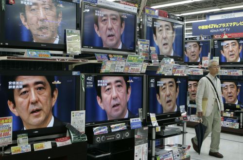 ياباني يمرّ أمام شاشات تلفزة خلال إعلان آبي استقالته في طوكيو أمس (يوريكو ناكاو - رويترز)