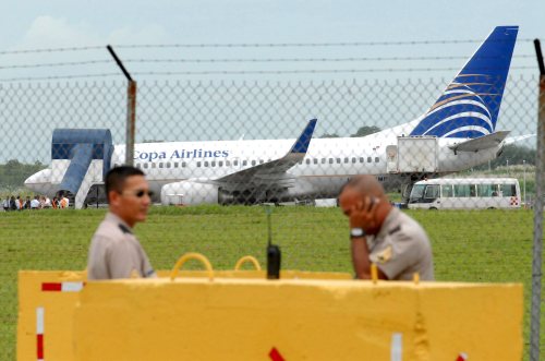 رجلا أمن بنميان وتبدو خلفهما الطائرة في مطار بنما سيتي (أليخاندرو بوليفار - إي بي أي)