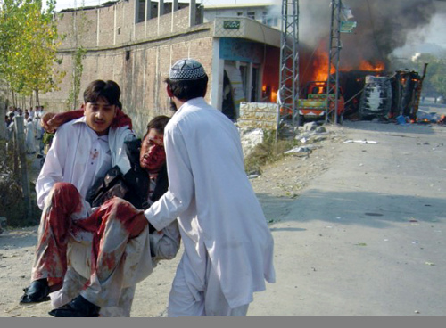 باكستانيان ينقلان جريحاً بعد التفجير في  المنطقة القبلية أمس (محمد إقبال - أ ب)