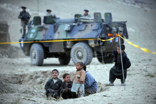 أطفال أفغان يلعبون بجانب جنود فرنسيّين في قرية زمّاه شمال كابول أوّل من أمس (مارتين بورو - أ ف ب)
