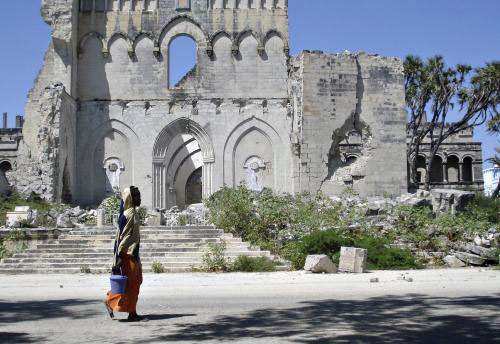 صومالية تمرّ أمام كنيسة مدمّرة في مقديشو الأسبوع الماضي (عمر فاروق - رويترز)