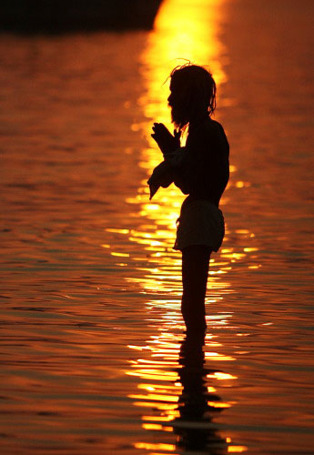 هندوسي يصلّي قرب نهر جنوب كلكوتا أمس (ديشاكاليان شودهوري - أ ف ب)