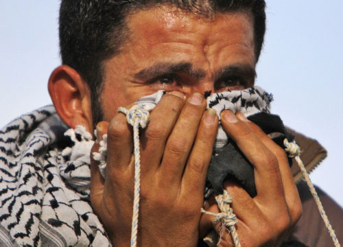 فلسطيني يحتمي من الغاز المسيّل للدموع خلال تظاهرة ضدّ الجدار في بلعين أمس (كيفين فراير ــ أ ب)