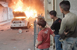أطفال فلسطينيون يراقبون سيارة محافظ نابلس تحترق في مخيّم بلاطة أمس (عبد عمر قوصني - رويترز)