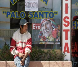 بوليفي يجلس أمام صورة لموراليس في حي {المشروع 3000» أمس (دايفد ميركادو - رويترز)
