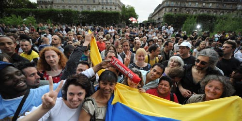 متظاهرون يرفعون العلم الكولومبي خلال الترحيب ببيتانكور في باريس أمس (ميغيل مدينا - أ ف ب)