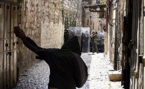 فلسطيني يرمي الجنود الإسرائيليين بالحجارة بعد اعتدائهم على الأقصى أمس (أحمد غرابلي - أ ف ب)