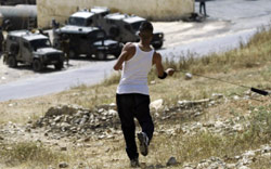 فتى فلسطيني ومقلاعه في مواجهة آليات إسرائيلية في الضفة الغربية أمس (مجدي محمد ــ أ ب)