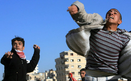 متظاهرون فلسطينيون يرمون حجارة على القوات المصرية عند رفح أول من أمس (محمد عبد - أ ف ب)