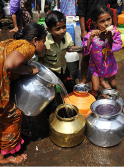 امرأة هندية تملأ وعاءً من الماء في مدينة مومباي (سجاد حسين ــ أ ف ب)