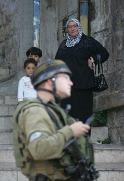 فلسطينية تراقب جندياً للاحتلال في الخليل (حازم بدر - أ ف ب)