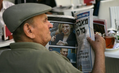 إسرائيلي يتابع أخبار الانتخابات في إحدى الصحف العبرية أمس (راشيل ستريشر - أ ب)