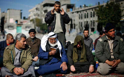 فلسطينيون يصلون على الطريق أمس بعد تهديم المساجد في غزة (أنجا نيدرينغوس - أ ب)