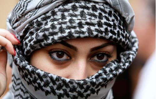 سعودية تغطي وجهها على غرار المقاتلين الفلسطينيين في يوم تضامني مع أطفال غزة في السفارة الفلسطينية في الرياض أمس (حسن عمار - أ ب)