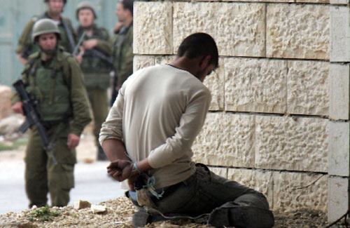 جنود إسرائيليون يعتقلون فلسطينياً خلال بحثهم عن الشاب الذي هاجم مستوطنَين في الضفة الغربية أمس (حازم بادر - أ ف ب)