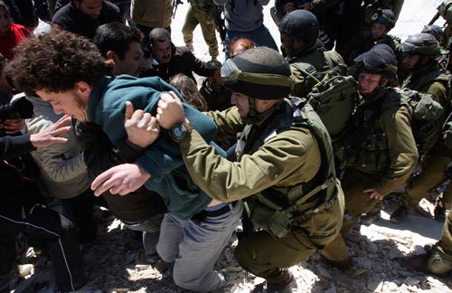 جنود إسرائيليون يضربون متظاهرين فلسطينيين خلال تعبيرهم عن رفضهم لحائط الفصل في الضفة الغربية  (نايف هشلمون - رويترز)
