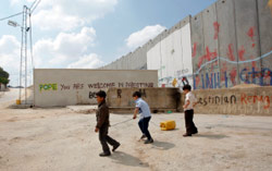 فلسطينيون بالقرب من الجدار العنصري وقد كتب عليه عبارة ترحيب بالبابا (ناصر شيوخي - أ ب)