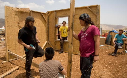 مستوطنون يعيدون بناء منزل في بؤرة ماعوز إستير بعدما أخلتها قوات الاحتلال أمس (سيبستيان شينر - أ ب)
