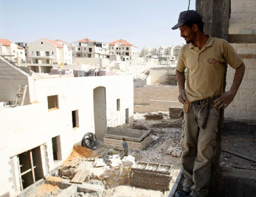 عامل فلسطيني يقف في مستوطنة معال أدوميم في الضفة الغربية الإثنين الماضي (باز راتنر - رويترز)