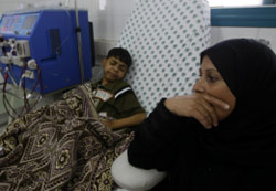 أم فلسطينية برفقة ابنها الذي يغسل كلى في مستشفى الشفاء في غزة (محمود حمص - أ ف ب)
