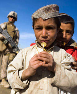 جندي من مشاة البحرية الأميركية خلف طفلان أفغانيان في إقليم نمروز (ماركو دجوريكا ـــ رويترز)