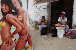 بائعتان تجلسان بالقرب من ملصق اعلاني في بلدة تيكيبايا التي تستضيف اليوم افتتاح «قمة الأرض الأم» (دادو غالدييري ــ أ ب)