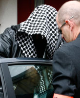 عنصر أمن يرافق الياس حباج إلى مقر الشرطة لاستجوابه (ستيفان ماهي ــ رويترز)