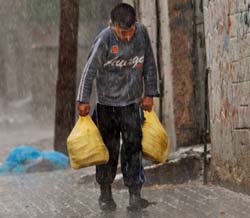 طفل فلسطيني ينقل أكياس خبز تحت المطر في قطاع غزّة أمس (حاتم موسى ــ أ ب)