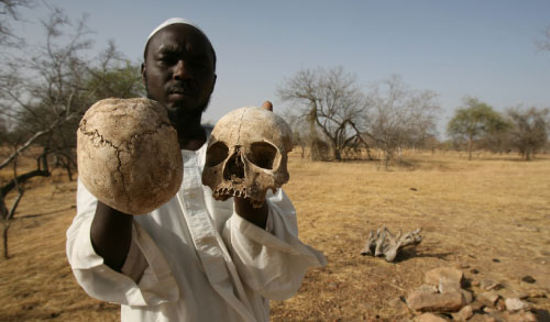 ناجٍ سوداني يحمل جماجم بشرية في إحدى المقابر الجماعية في دارفور (ناصر ناصر - أ ب)
