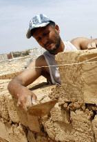 عامل فلسطيني يبني منزلاً من الطين في مخيم رفح (سعيد خطيب ــ أ ف ب)