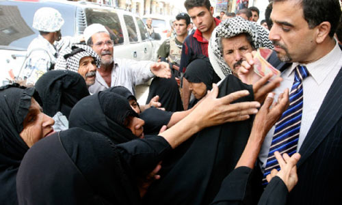 مساعد برهم صالح يوزّع الأموال على العراقيين في النجف أمس (علي أبو شيش ـــ رويترز)