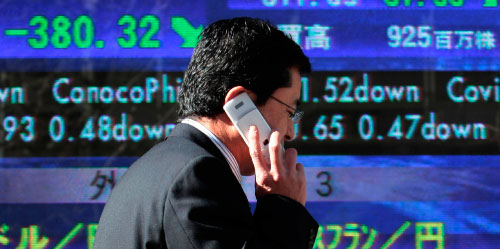 رجل أعمال ياباني أمام لوحة إلكترونيّة للمؤشّرات الماليّة في طوكيو (إتسوو إينوي ــ أ ب)