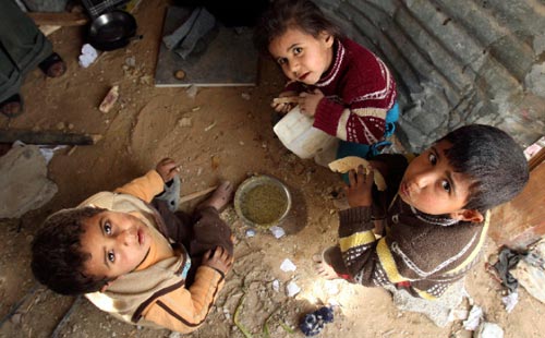 أطفال فلسطينيون يتناولون الغداء في جباليا أمس (سهيب سالم ــ رويترز)