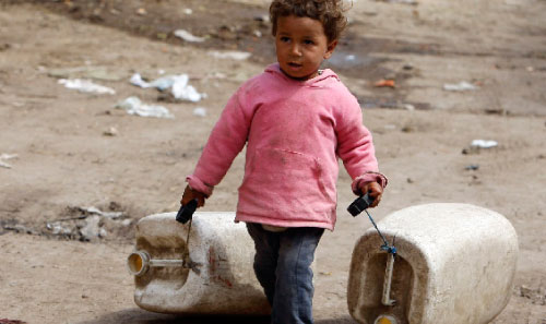 طفلة مصريّة تجرّ غالونين لتعبئتهما بالمياه في القاهرة الشهر الماضي (عمر عبد الله - رويترز)