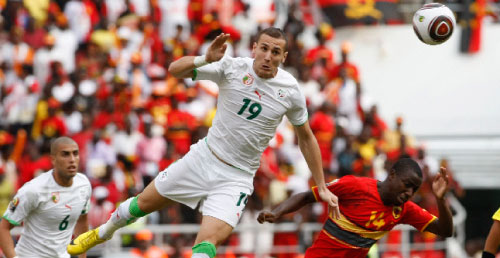 يبدا لاعب الجزائر يرتقي للكرة قبل ديالما من انغولا (مايك هوتشينغيز ــ رويترز)